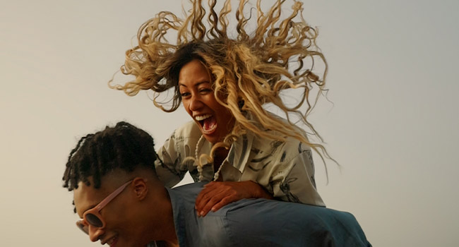 freeze-frame of tanned asian young woman with long curly blonde hair flying all around