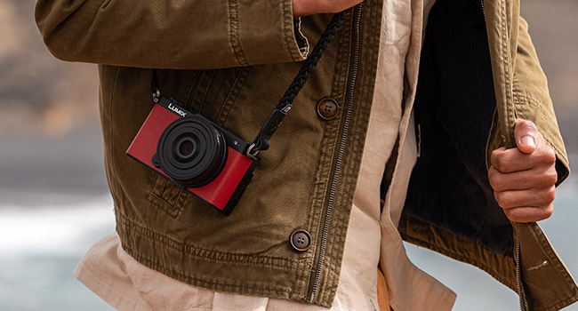 crop of man in an olive jacket with a red LUMIX S9 camera.